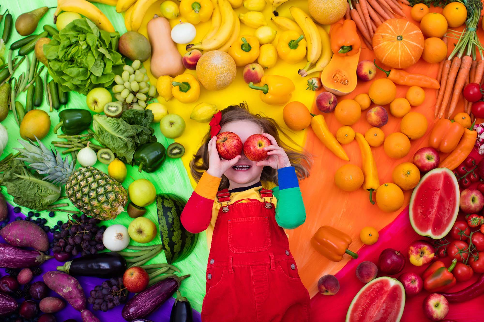 kid with colorful fruits and veggies smiling